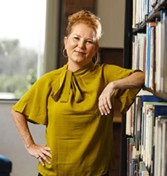 MCC Scholarship/Financial 援助 recipient Paula Barlow leaning up against a bookshelf.